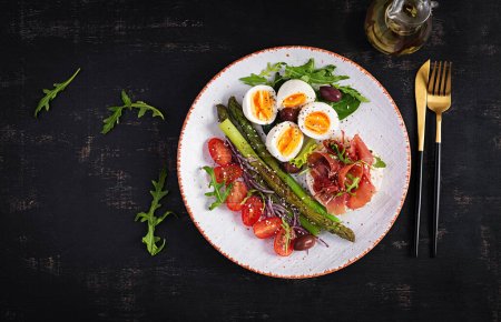 Photo for Keto breakfast. Fried asparagus with boiled eggs and toast with prosciutto or jamon. Ketogenic diet. Healthy food. Top view, flat lay - Royalty Free Image