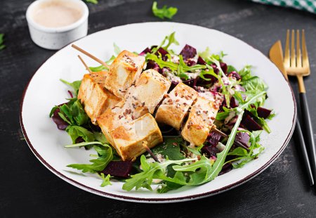 Foto de Brochetas de tofu al horno en salsa y ensalada de remolacha, rúcula con salsa de yogur vegetal. Concepto de comida vegana saludable. Alimento saludable. - Imagen libre de derechos