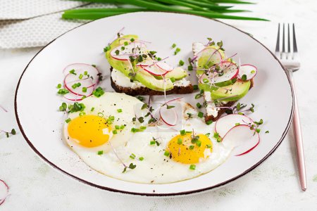 Foto de Huevos fritos y sándwiches con aguacate y rábano para un desayuno saludable. - Imagen libre de derechos