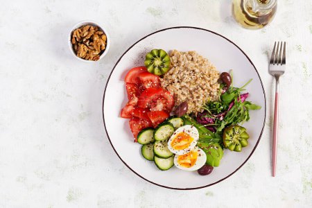 Photo for Breakfast oatmeal porridge with boiled eggs, fresh salad and kiwi. Healthy balanced food. Top view, overhead - Royalty Free Image