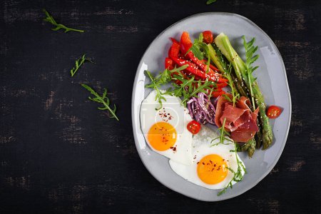 Photo for Keto breakfast. Fried asparagus with roasted eggs and  prosciutto or jamon. Ketogenic diet. Healthy food. Top view, flat lay - Royalty Free Image
