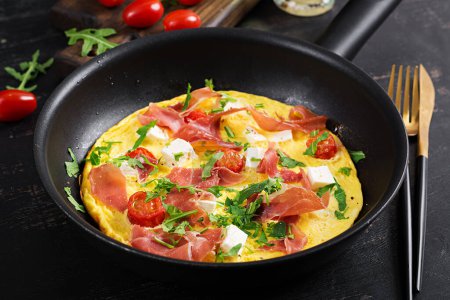 Photo for Omelet with tomatoes, jamon and feta cheese in pan. - Royalty Free Image