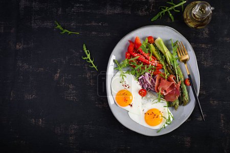 Téléchargez les photos : Petit déjeuner Keto. Asperges frites aux œufs rôtis et prosciutto ou jamon. Régime cétogène. Une nourriture saine. Vue de dessus, plan plat - en image libre de droit