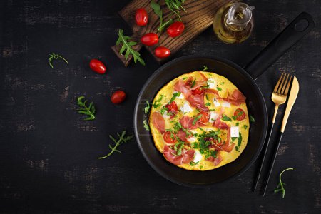 Photo for Omelet with tomatoes, jamon and feta cheese in pan. Top view - Royalty Free Image