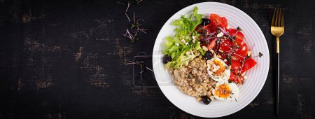 Téléchargez les photos : Petit déjeuner gruau d'avoine avec oeuf bouilli, tomates cerises, olives, noix et microgreens. Alimentation saine et équilibrée. Vue de dessus, vue aérienne - en image libre de droit