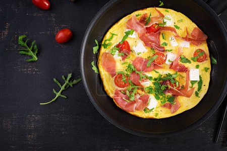 Téléchargez les photos : Omelette aux tomates, jamon et fromage feta dans une casserole. Vue du dessus - en image libre de droit