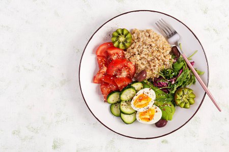 Téléchargez les photos : Petit déjeuner bouillie de flocons d'avoine avec œufs durs, salade fraîche et kiwi. Alimentation saine et équilibrée. Vue de dessus, vue aérienne - en image libre de droit