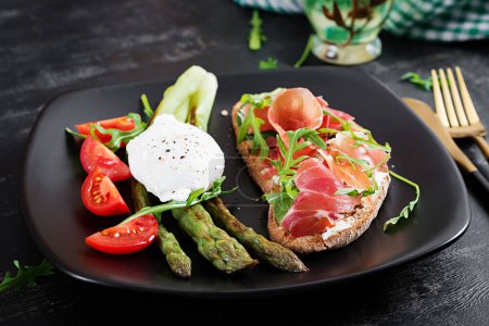 Photo for Keto breakfast. Fried asparagus with poached egg and toast with prosciutto or jamon. Ketogenic diet. Healthy food. - Royalty Free Image