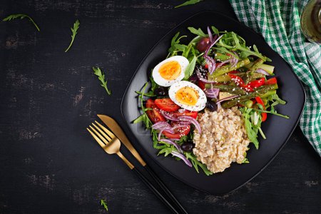 Photo for Breakfast oatmeal porridge with boiled egg, cherry tomatoes, asparagus and arugula. Healthy balanced food. Top view, overhead - Royalty Free Image