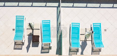 Foto de Tumbona con sombrilla y accesorios de playa para el descanso activo en la piscina, espacio para copiar, vista superior - Imagen libre de derechos