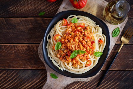 Foto de Pasta de espaguetis y salsa de tomate con carne de pollo picada sobre un fondo de madera. Pasta boloñesa. Vista superior - Imagen libre de derechos