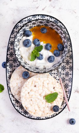 Photo for Cottage cheese with honey and blueberries and rice cakes. Diet breakfast. Top view - Royalty Free Image