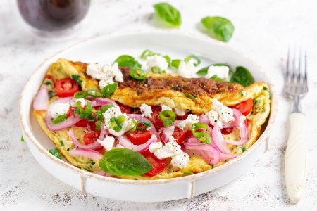Téléchargez les photos : Omelette aux tomates, fromage feta et oignon rouge sur assiette blanche. Frittata - omelette italienne. - en image libre de droit
