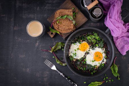 Photo for Breakfast. Fried eggs with green beet leaves, garlic, pepper and green onion in pan. Top view, flat lay - Royalty Free Image