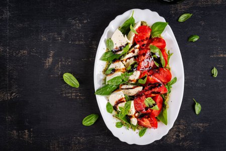 Téléchargez les photos : Caprese tomate salade pour la conception de concept. Fond sombre, gros plan. Concept de nourriture. Vue du dessus - en image libre de droit