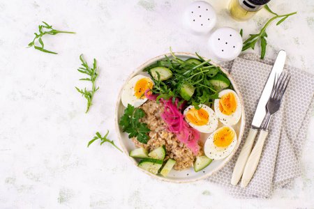 Foto de Desayuno gachas de avena con huevos cocidos, pepino, cebolla roja y verduras. Comida sana y equilibrada. Vista superior - Imagen libre de derechos