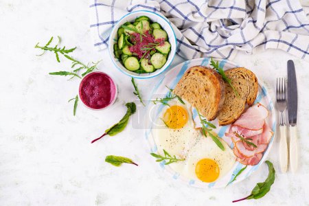 Photo for Breakfast. Fried egg, slices of ham, toasted bread and beetroot smoothie. Top view - Royalty Free Image