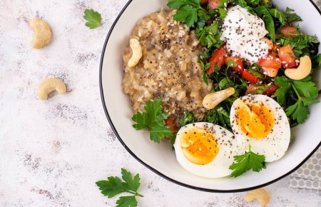 Téléchargez les photos : Petit déjeuner porridge à base de flocons d'avoine avec œufs durs et salade fraîche. Alimentation saine et équilibrée. Nourriture tendance. Vue du dessus - en image libre de droit