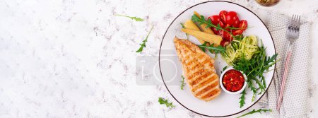 Photo for Healthy keto, ketogenic lunch with grilled chicken  breast, fillet and  salad of arugula, onion, boiled corn, cucumber and tomato. Roasted chicken meat and salad. Top view, banner - Royalty Free Image