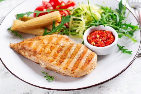 Photo for Healthy keto, ketogenic lunch with grilled chicken  breast, fillet and  salad of arugula, onion, boiled corn, cucumber and tomato. Roasted chicken meat and salad. - Royalty Free Image