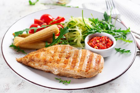 Téléchargez les photos : Céto sain, déjeuner cétogène avec poitrine de poulet grillée, filet et salade de roquette, oignon, maïs bouilli, concombre et tomate. Viande de poulet rôtie et salade. - en image libre de droit