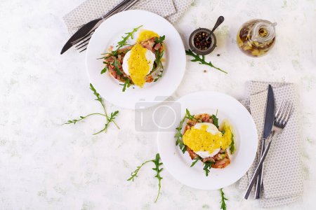Photo for Breakfast. Sandwich with ham, poached egg, onion and arugula in a plate on a light background. Top view - Royalty Free Image