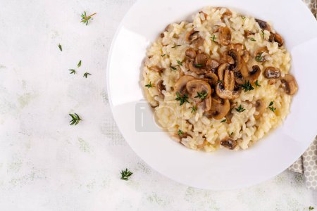 Téléchargez les photos : Plat avec de délicieux risotto aux champignons dans une assiette. Porridge de riz avec champignon et tmyne. Plat chaud, cuisine italienne. Vue du dessus - en image libre de droit