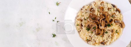 Téléchargez les photos : Plat avec de délicieux risotto aux champignons dans une assiette. Porridge de riz avec champignon et tmyne. Plat chaud, cuisine italienne. Vue du dessus, bannière - en image libre de droit