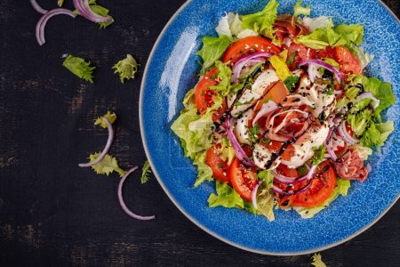 Téléchargez les photos : Salade avec prosciutto, mozzarella, tomates et oignon rouge. Une saine alimentation. Keto, régime cétogène. Vue du dessus - en image libre de droit