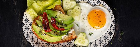 Photo for Romantic breakfast for Valentine's Day. Fried egg and toast with avocado and cream cheese. Top view, banner - Royalty Free Image