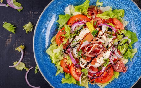Photo for Salad with prosciutto, mozzarella, tomatoes and red onion. Healthy eating. Keto, ketogenic diet. Top view - Royalty Free Image