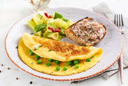 Téléchargez les photos : Omelette aux petits pois verts et pain grillé au foie de morue sur plaque blanche. Frittata - omelette italienne. - en image libre de droit