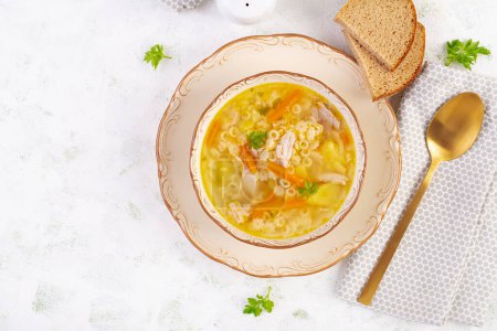 Téléchargez les photos : Soupe de poulet fraîche aux légumes et pâtes stellines dans un bol avec carotte et persil. Vue de dessus, plan plat - en image libre de droit