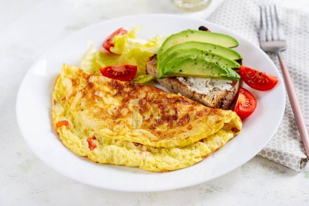 Photo for Omelette with tomatoes and toast with avocado on white plate.  Frittata - italian omelet. - Royalty Free Image