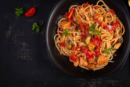 Téléchargez les photos : Pâtes italiennes classiques spaghetti marinara aux moules et au saumon sur table noire. Pâtes spaghetti à la sauce marinara. Vue de dessus, vue aérienne - en image libre de droit