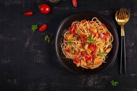 Photo for Classic italian pasta spaghetti marinara with mussels and salmon on dark table. Spaghetti pasta with sauce marinara. Top view, overhead - Royalty Free Image