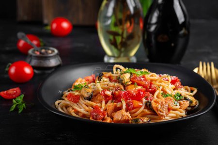 Photo for Classic italian pasta spaghetti marinara with mussels and salmon on dark table. Spaghetti pasta with sauce marinara. - Royalty Free Image