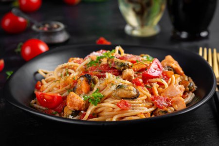 Téléchargez les photos : Pâtes italiennes classiques spaghetti marinara aux moules et au saumon sur table noire. Pâtes spaghetti à la sauce marinara. - en image libre de droit