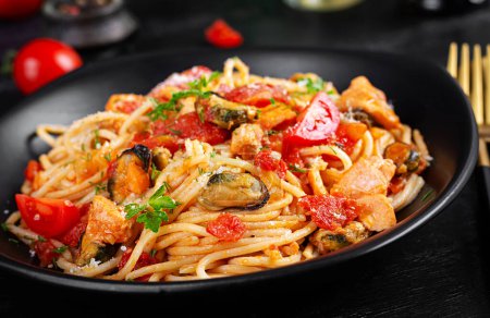 Photo for Classic italian pasta spaghetti marinara with mussels and salmon on dark table. Spaghetti pasta with sauce marinara. - Royalty Free Image