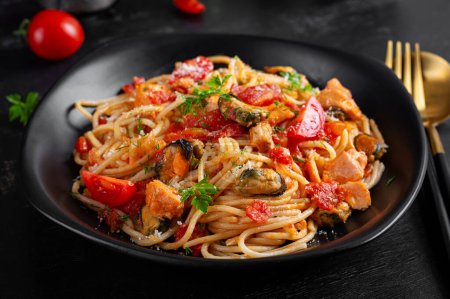 Foto de Pasta italiana clásica de espaguetis marinara con mejillones y salmón sobre mesa oscura. Pasta de espagueti con salsa marinara. - Imagen libre de derechos