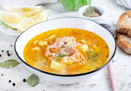 Foto de Sopa de pescado con salmón, verduras y arroz en tazón blanco. Sopa de salmón. - Imagen libre de derechos
