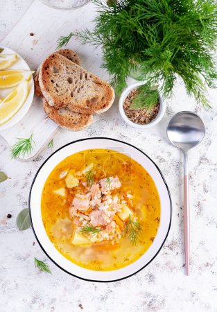 Foto de Sopa de pescado con salmón, verduras y arroz en tazón blanco. Sopa de salmón. Vista superior, plano - Imagen libre de derechos