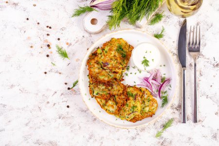 Photo for Zucchini fritters with red onions, garlic and herbs. Vegetarian zucchini pancakes and sour cream on white table. Top view - Royalty Free Image