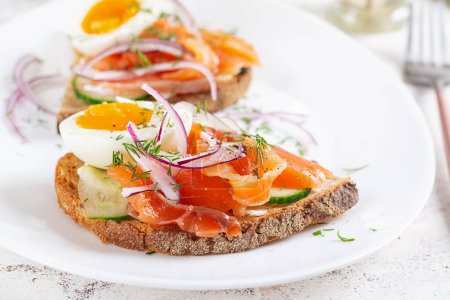 Photo for Delicious toast with salmon, boiled egg, cucumber and cream cheese on a white plate. Healthy eating, breakfast. Keto diet food. Tasty food. - Royalty Free Image