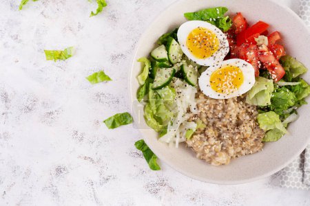 Photo for Breakfast oatmeal porridge with boiled eggs, tomato, cucumber and onions. Healthy balanced food. Trendy food. Top view, flat lay - Royalty Free Image