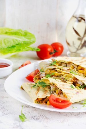 Téléchargez les photos : Quesadilla mexicain envelopper avec du poulet, du maïs et du poivron sur une assiette blanche. - en image libre de droit