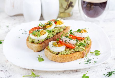Photo for Delicious toast with avocado, boiled egg, tomatoes and microgreen on a white plate. Healthy eating, breakfast. Keto diet food. Trendy food. - Royalty Free Image