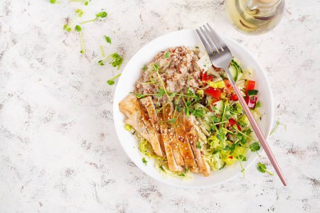 Photo for Lunch oatmeal porridge with grilled chicken fillet and fresh vegetables. Healthy balanced food. Trendy food. Top view, flat lay - Royalty Free Image