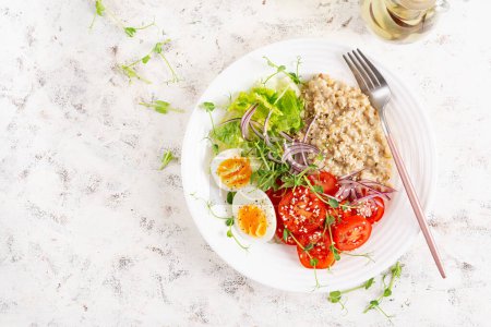 Photo for Breakfast oatmeal porridge with boiled eggs and fresh vegetables. Healthy balanced food. Trendy food. Top view, flat lay - Royalty Free Image
