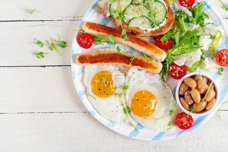 Photo for English breakfast. Keto breakfast. Fried egg, beans, chicken sausage. Top view, flat lay - Royalty Free Image
